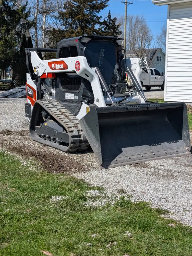 Busy Man Contracting Bobcat loader parked on a gravel drive
